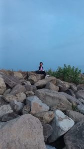 Duduk di atas bebatuan tepi pantai